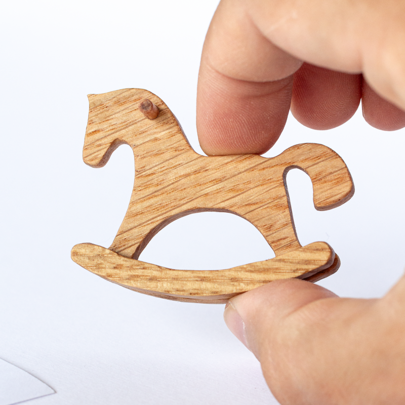 Miniature wooden rocking horse held in fingers – actual size, 1:12 dollhouse scale