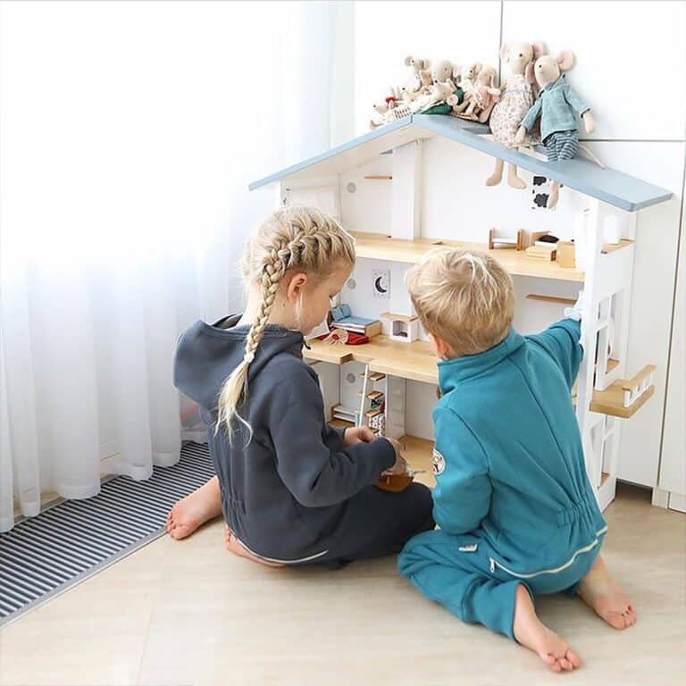 A brother and sister sharing playtime with their Katin Domik gender neutral wooden dollhouse.