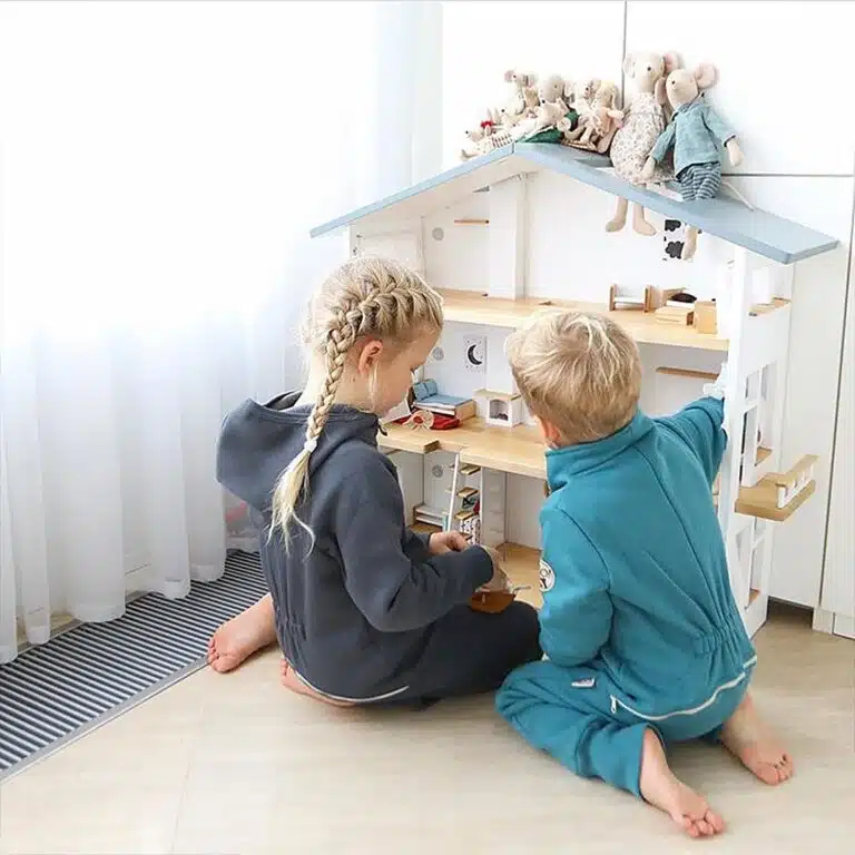 A brother and sister sharing playtime with their Katin Domik gender neutral wooden dollhouse.
