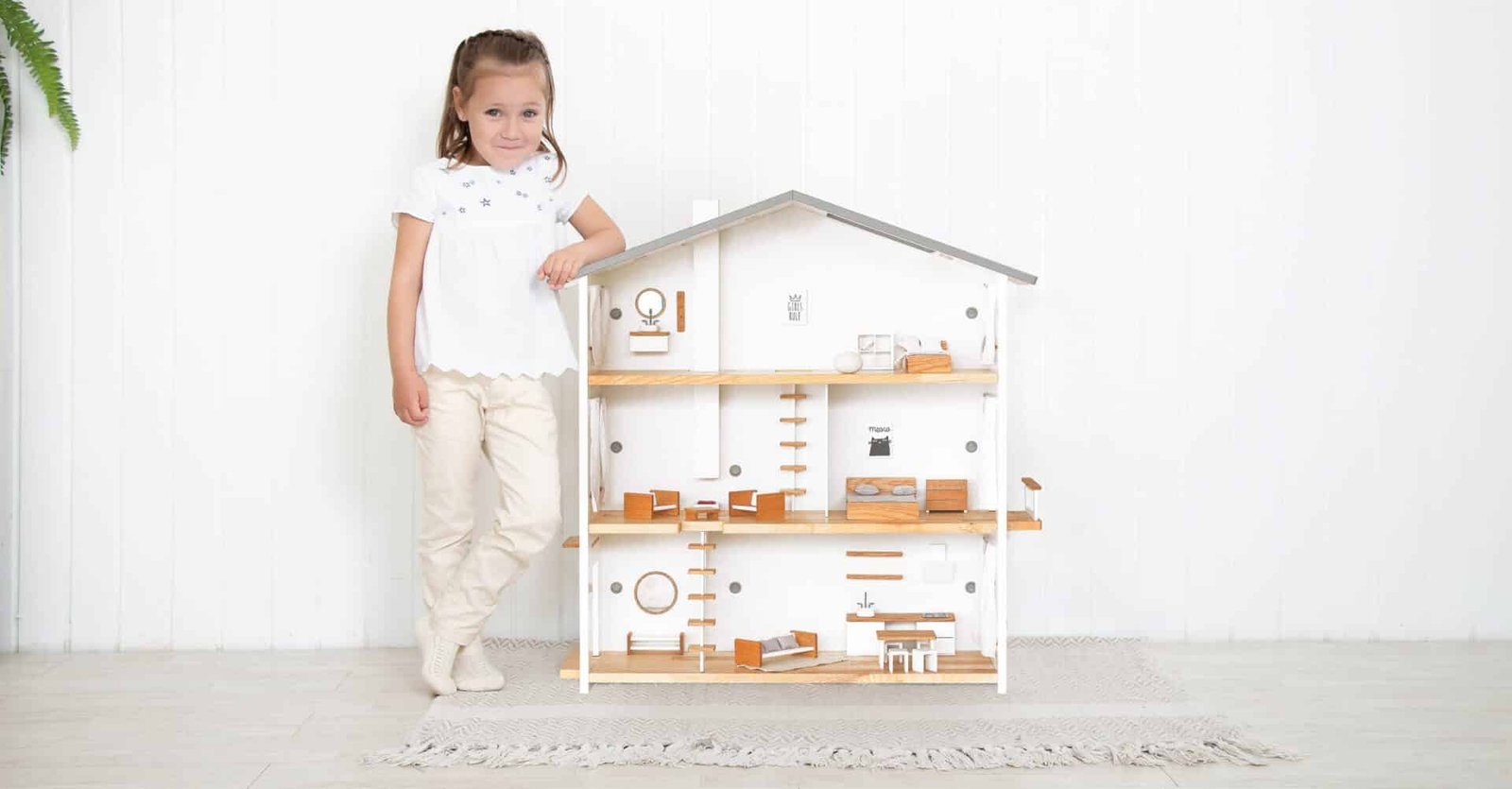 Modern design three-storey wooden dollhouse with child showing scale – white walls, oak floors, Katin Domik