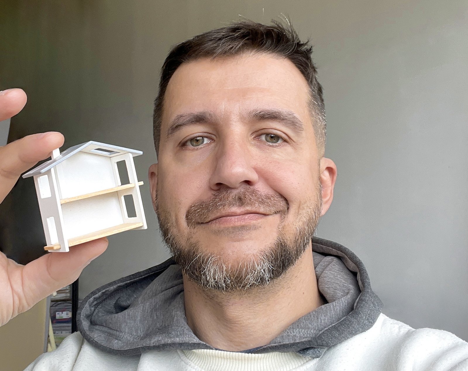 Nik Strelkov, designer of Katin Domik, holding a handmade wooden dollhouse prototype